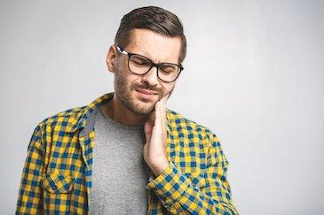 man holding jaw from TMJ pain