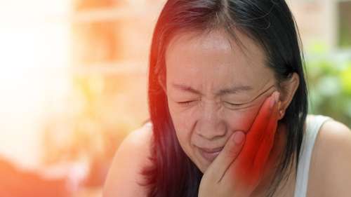 woman holding jaw from TMJ pain