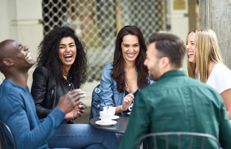 group of friends laughing while drinking coffee